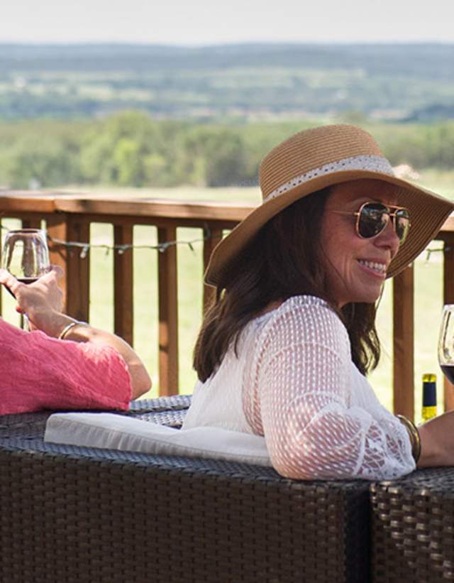 Four women looking out at the hill country with wine glasses in hand.