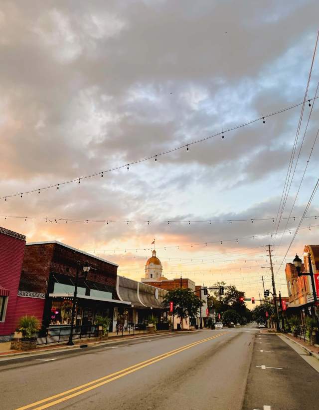 Downtown Columbiana Main Street shot from the road with string lights overhead and a sunset in the background.