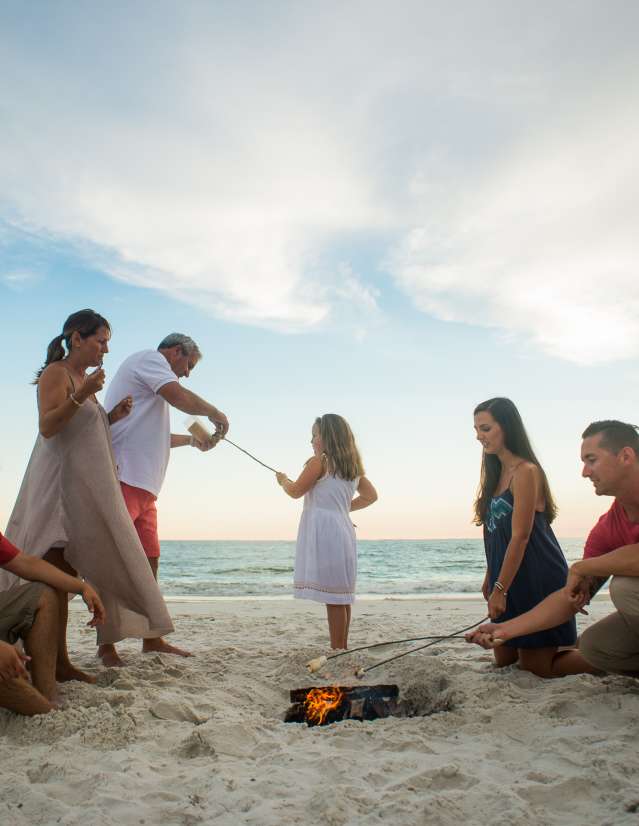 A family has a bonfire on the beach