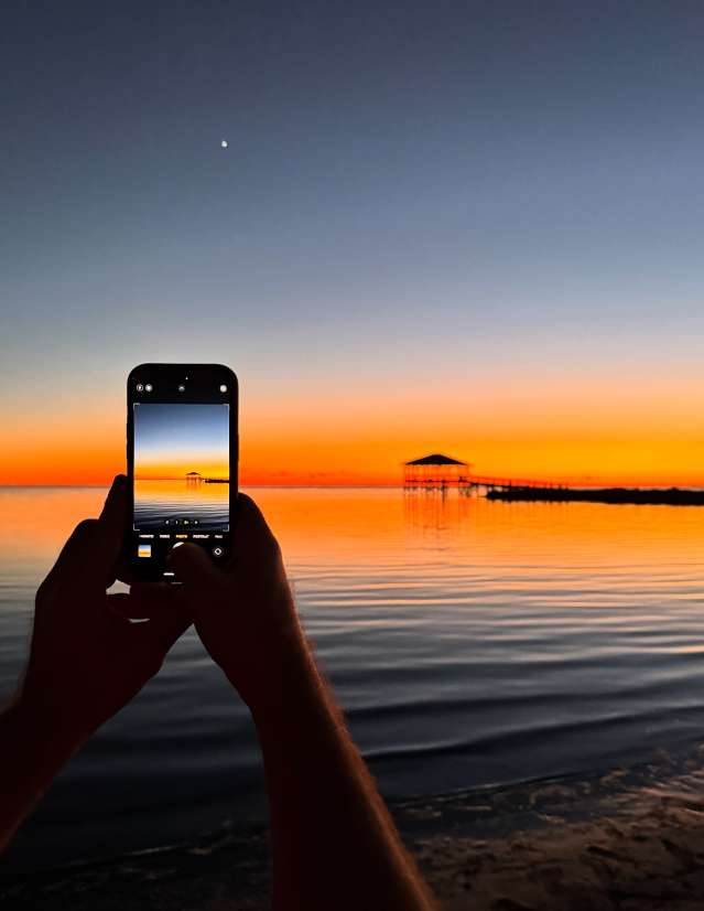 Someone takes a twilgiht photo of a pier at sunset