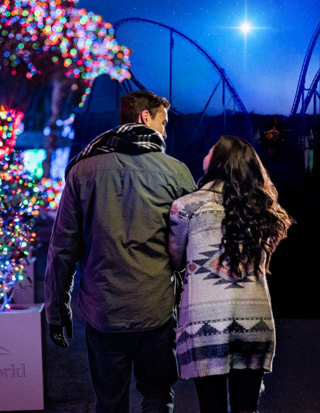 Couple walking side by side next to trees lit with holiday lights