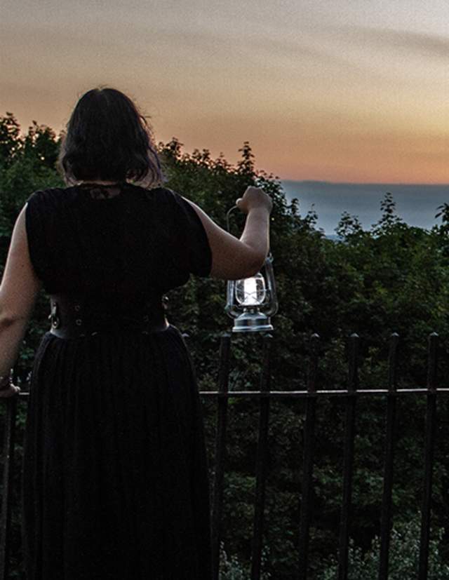 Woman holding a lantern looking at the state house during a Providence Ghost Tour