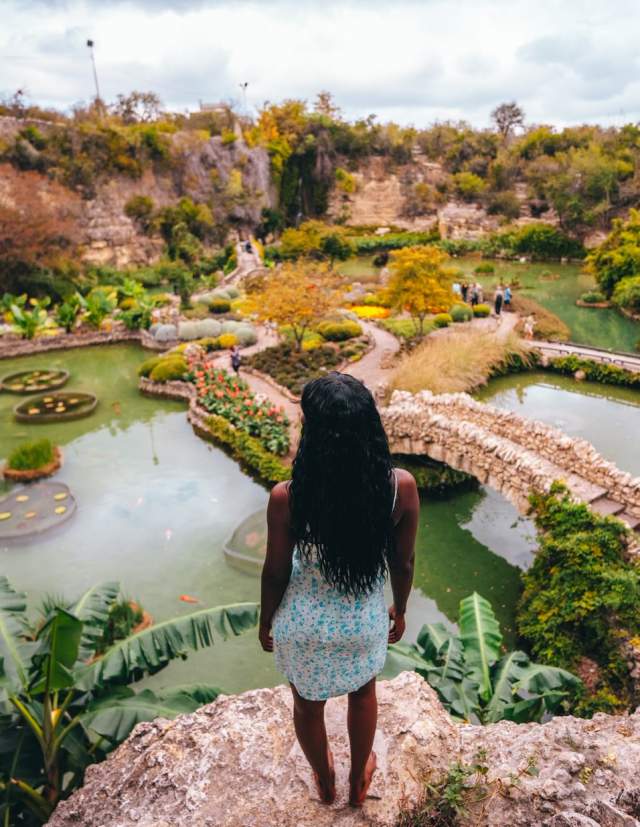 Woman overlooking lush garden and standing water