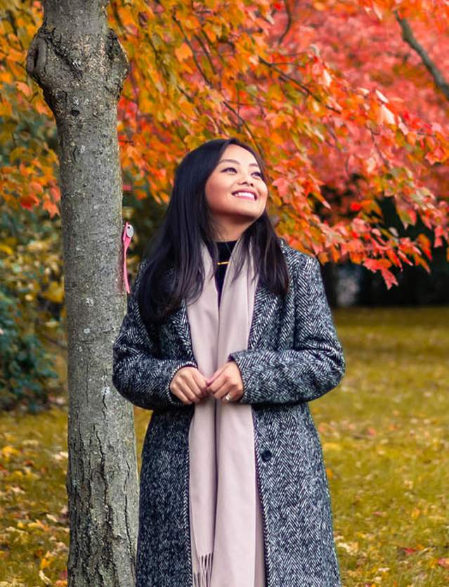 Woman in coat and scarf walking in a fall scene