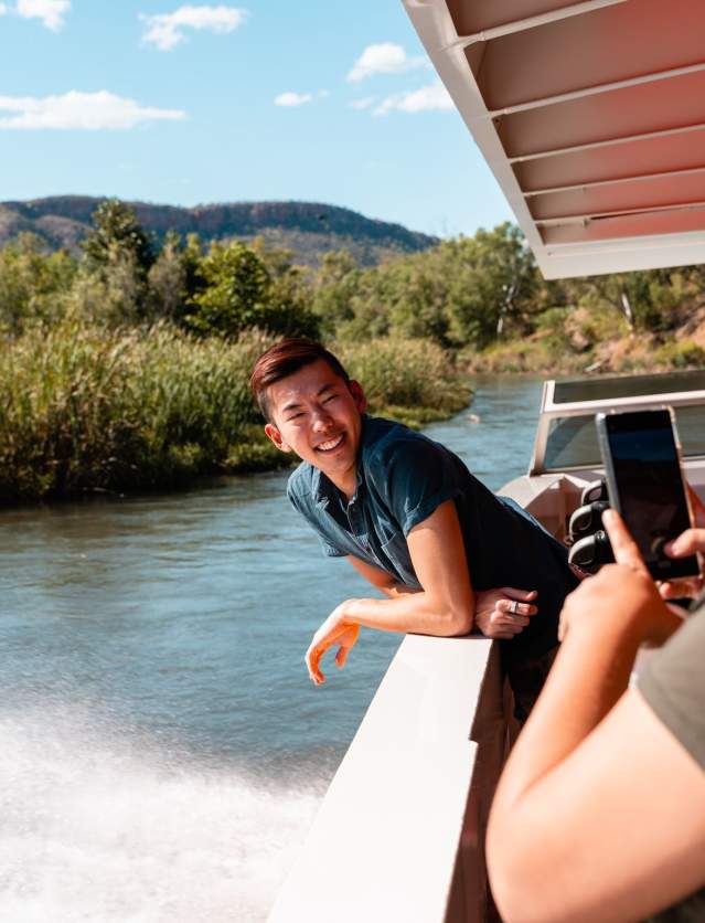 Passengers on a Triple J Ord River boat tour take a photo as the boat moves through the scenery