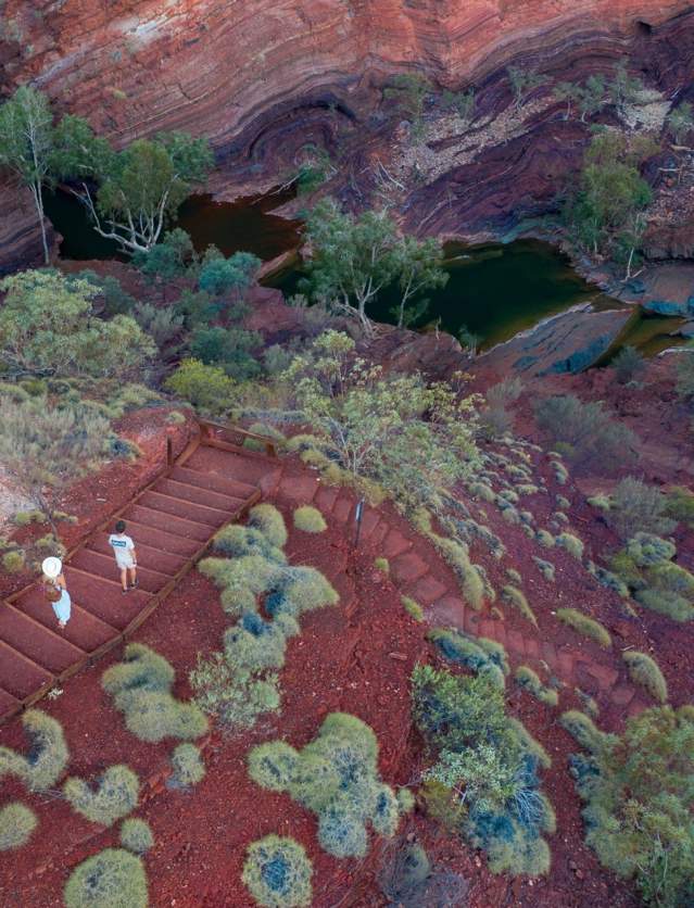A couple walking down steps leading into Hamersley Gorge in Karijini National Park