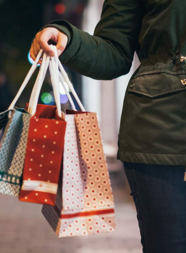 Picture of person holding shopping bags with downtown street view in background.