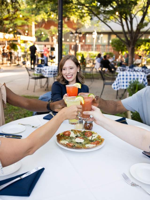A group of friends toasts at an outdoor dining table in Paducah, KY.
