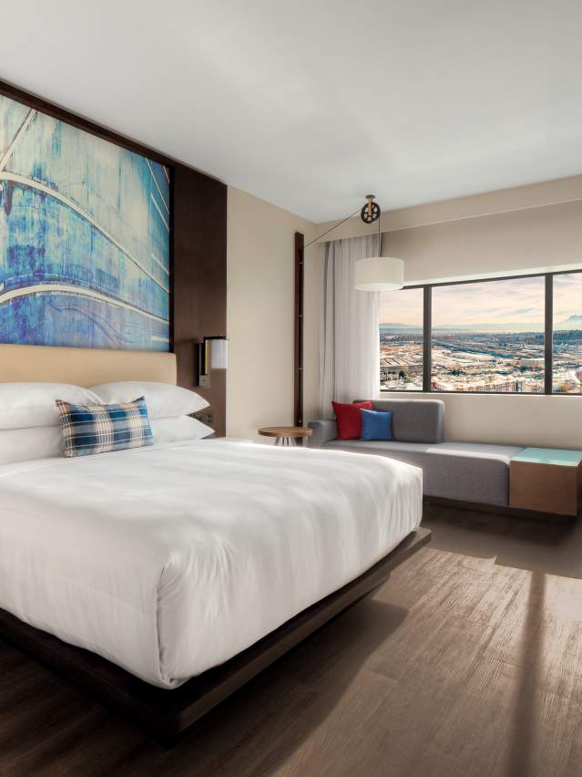 A king guest room with a sofa, desk and a window overlooking the city and Mount Rainier.