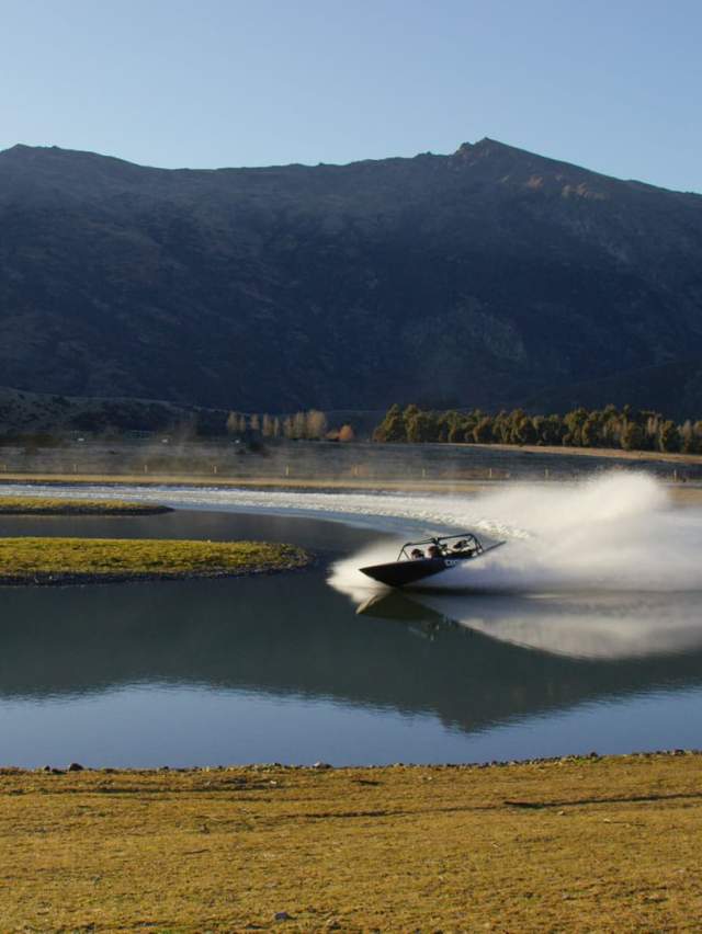 Jet boat on a lake in front of mountains