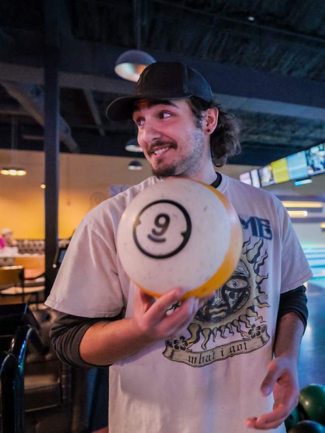 A man holds a bowling ball while looking back towards friends during a night out at 810 Billiards and Bowling, Fort Smith.