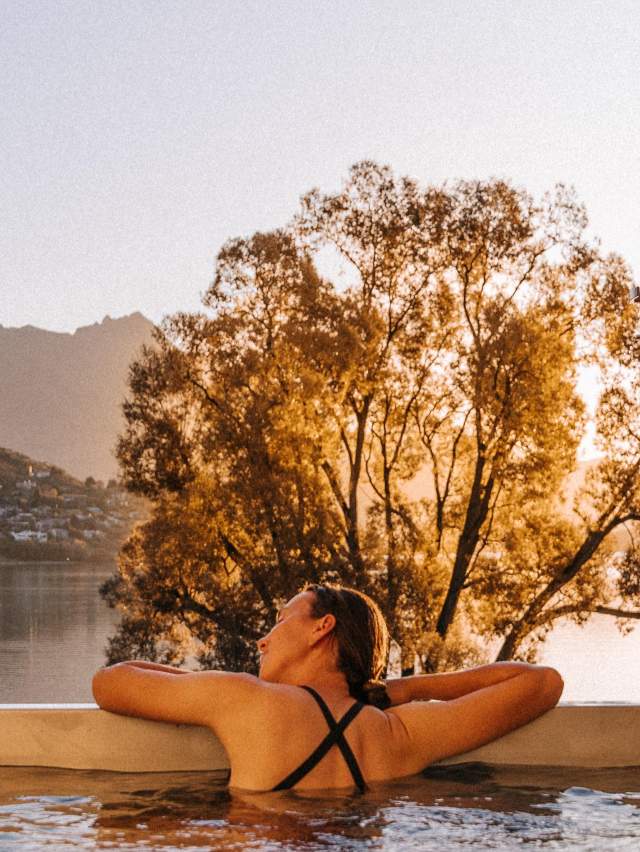 Person in hot tub with mountain and lake views in the background