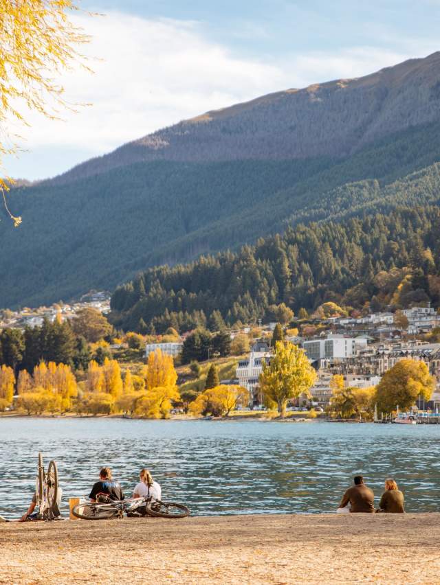 Peolple sitting at a beach in Autumn with town and mountain views