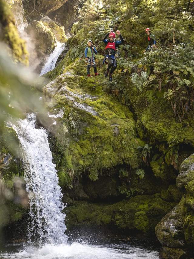 Person canyoning, jumping off a waterfall into a natural spring