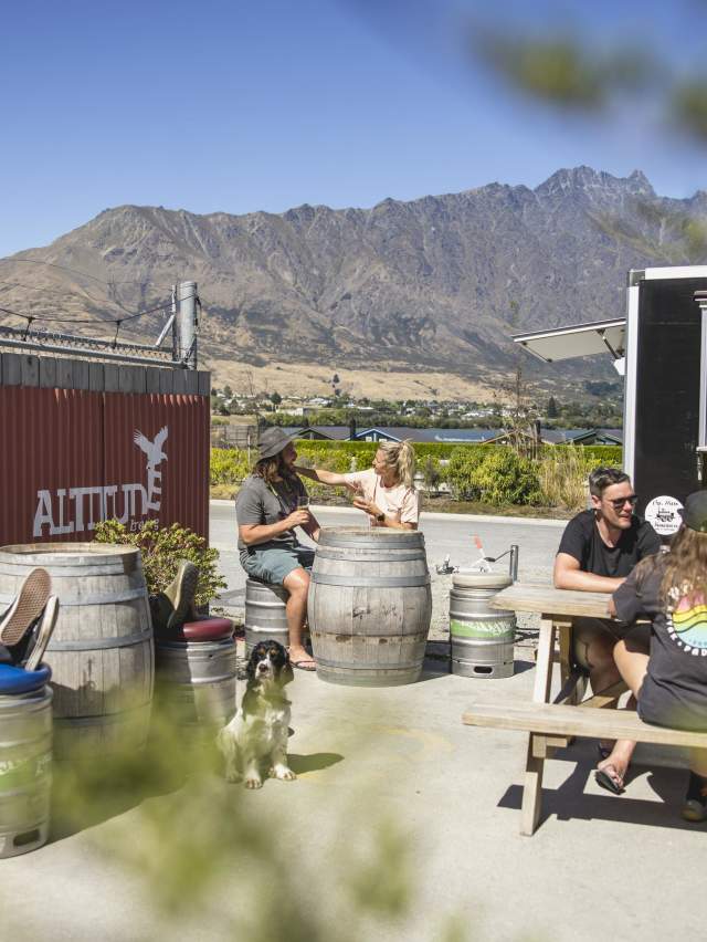 People sitting in the outdoor beer garden at Altitude Brewing with the Remarkables mountains in the background