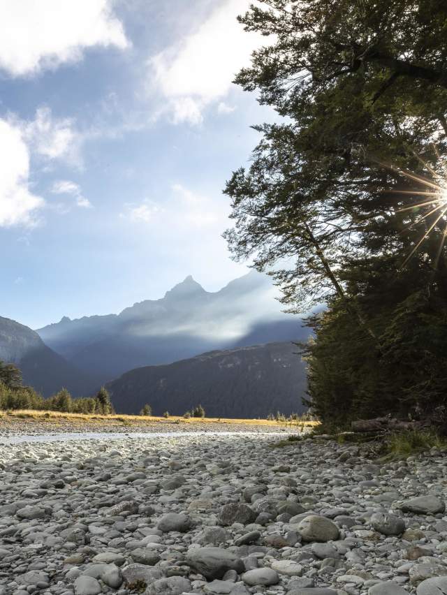 Scenic photo of a river and mountains from a rocky shore