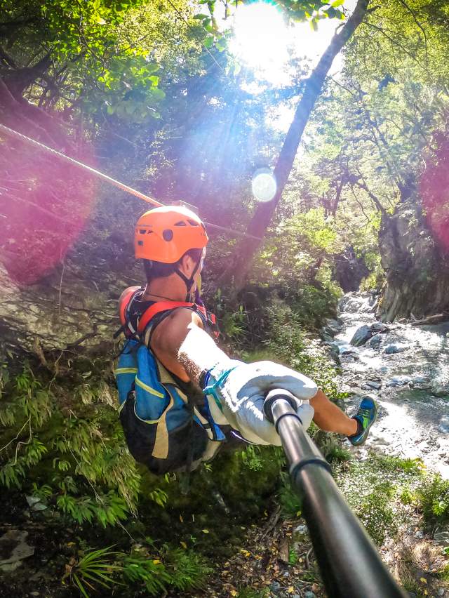 Person ziplining through a forest, over a river
