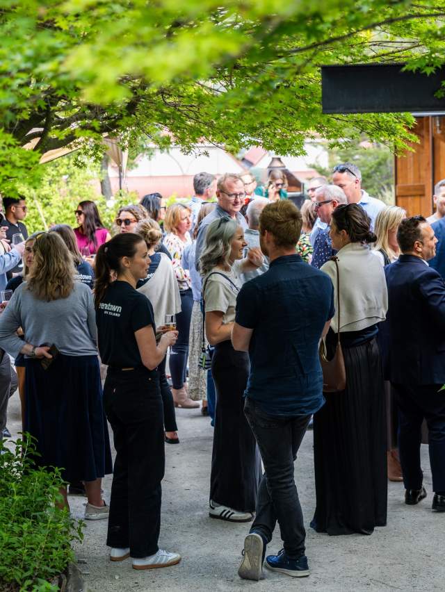A group of people mingling outside at the Sherwood with trees surrounding the frame