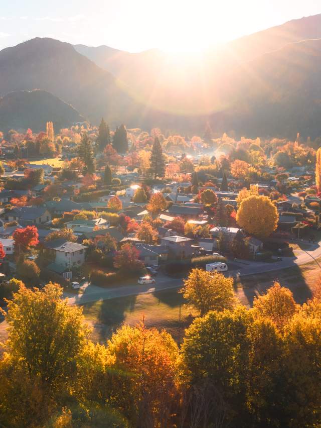 Aerial photo of Arrowtown full of gold and red trees in Autumn