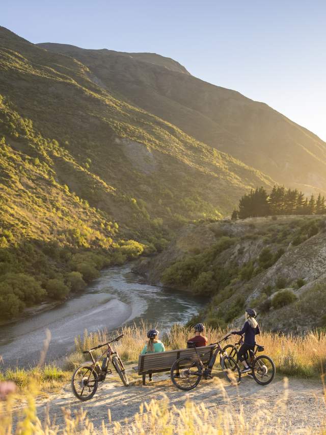 A group of cyclists taking a break next to Gibbston River