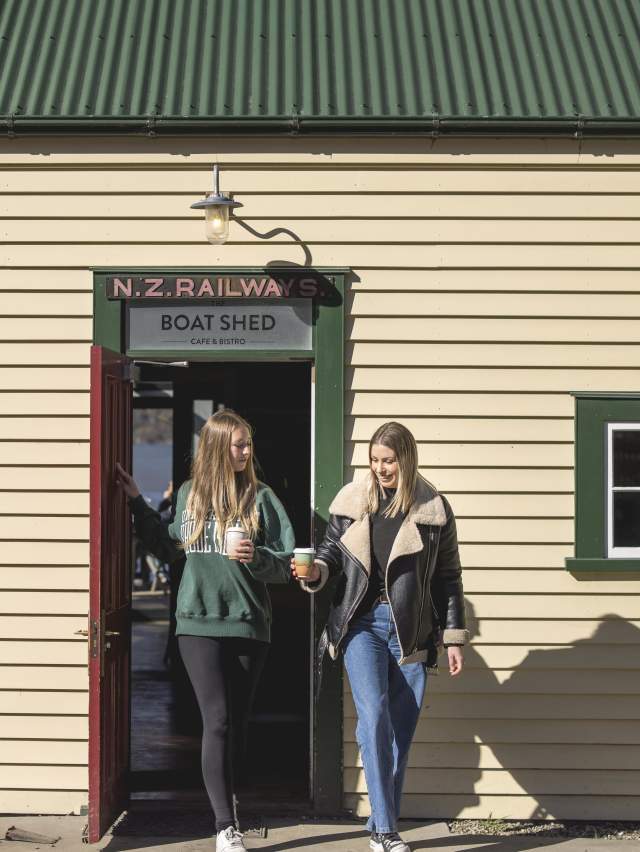 Two people walking out of the Boat Shed Café with keep cups