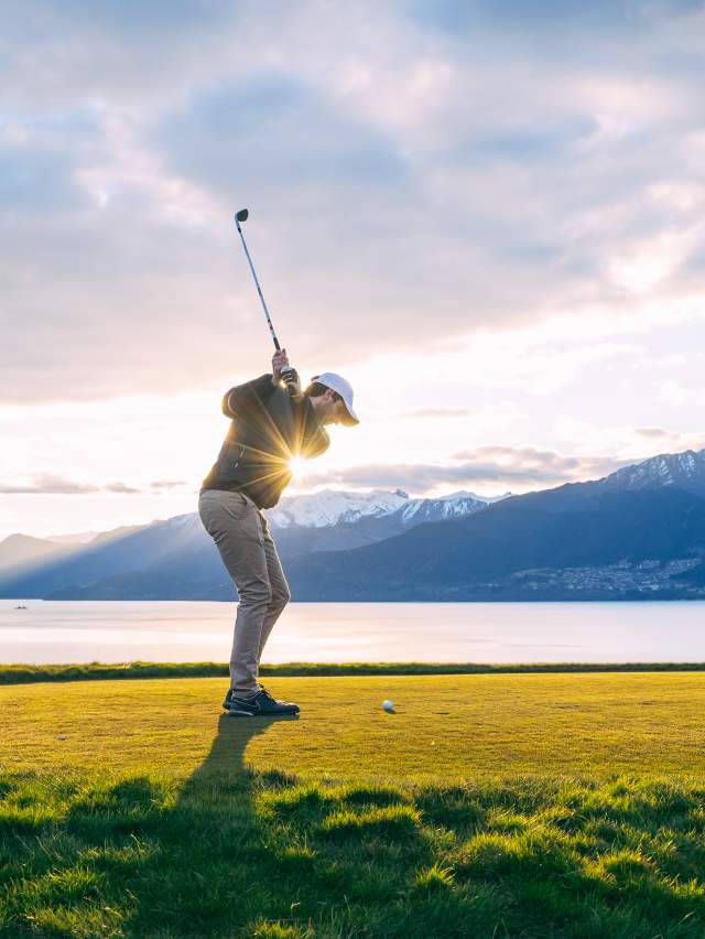 Man golfing with lake and mountain views