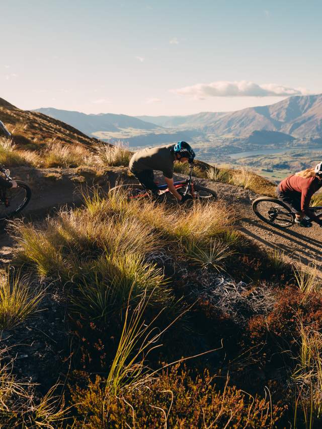 Group of downhill mountain bikers shredding Coronet Peak, Queenstown overlooking valley