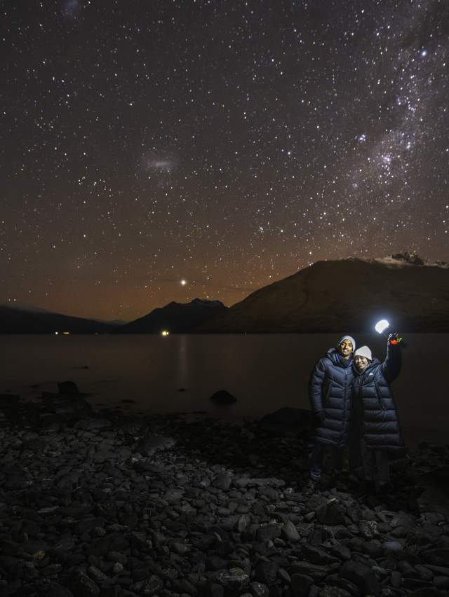 People standing on the lakefront with a starry night sky behind them