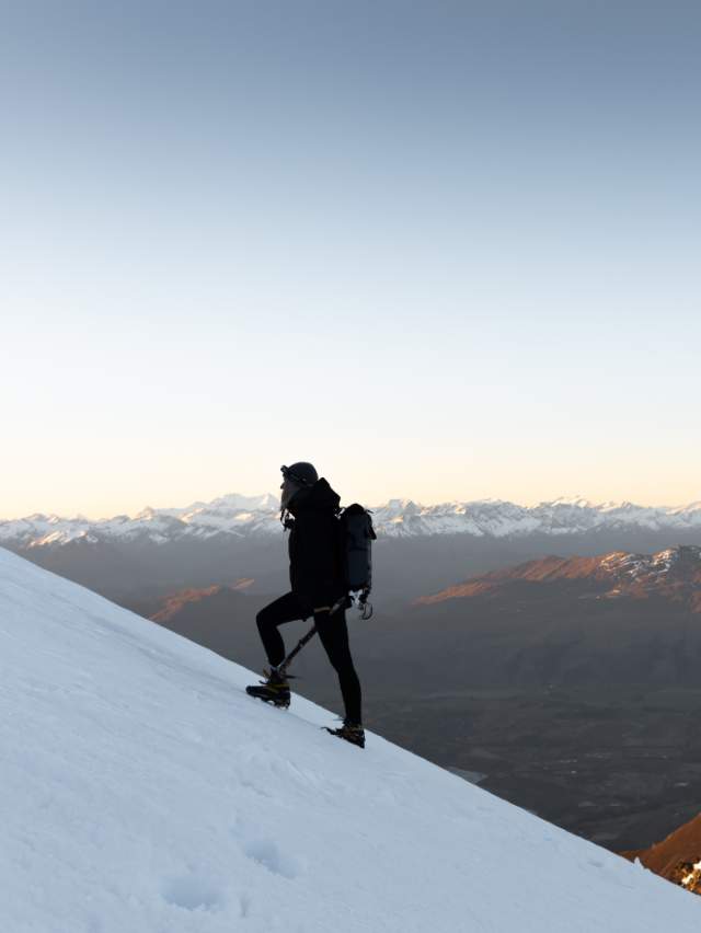 Woman hiking up the side of a snowy mountain in winter