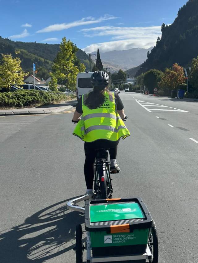 Women on bike with trailer rides along road to collect unused food from local cafes