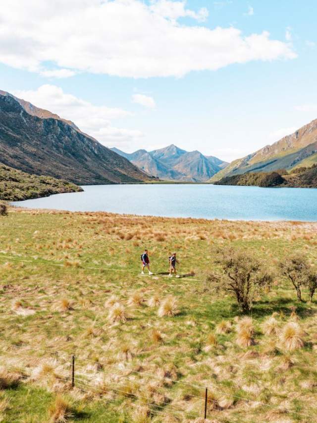 Two people walking Moke Lake Loop Track with lake and mountains in view
