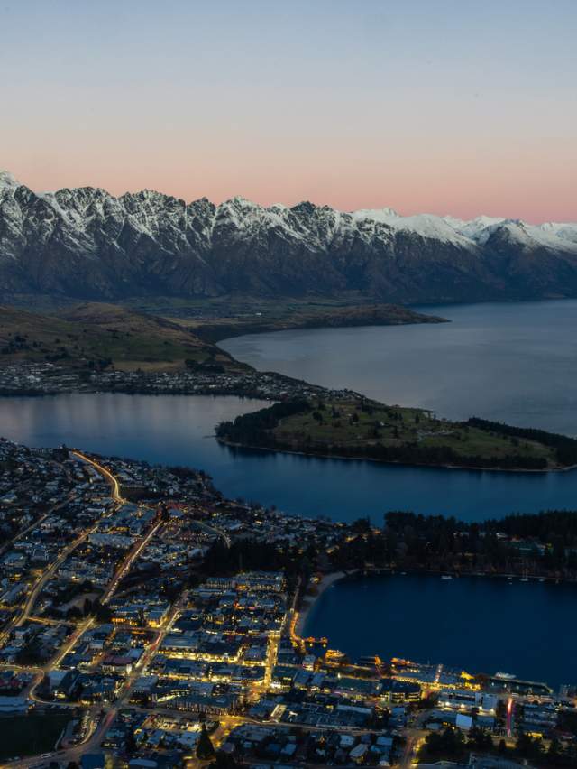 Aerial view of Queenstown at dusk with the Remarkables mountain range covered in snow