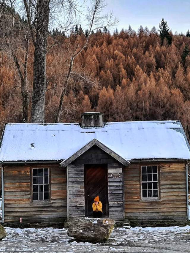 Person sits outside histroric Police Hut Arrowtown