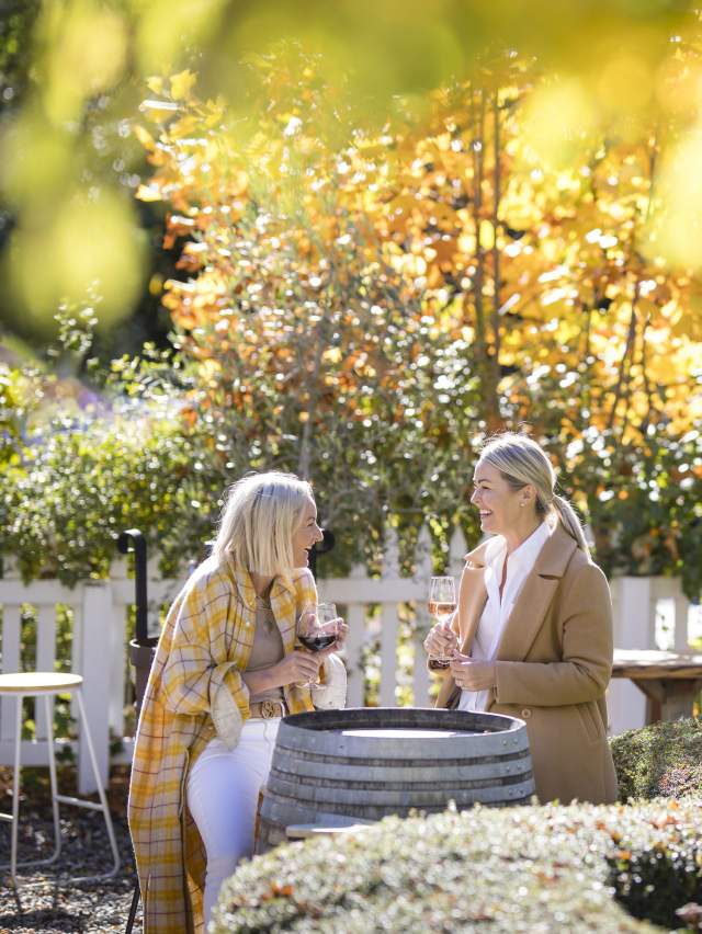 Two people enjoying wine in a outdoor garden dining aera in autumn