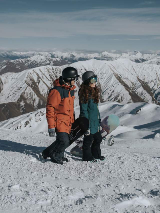 Couple holding snowboards on top of mountain Cardrona Alpine Resort