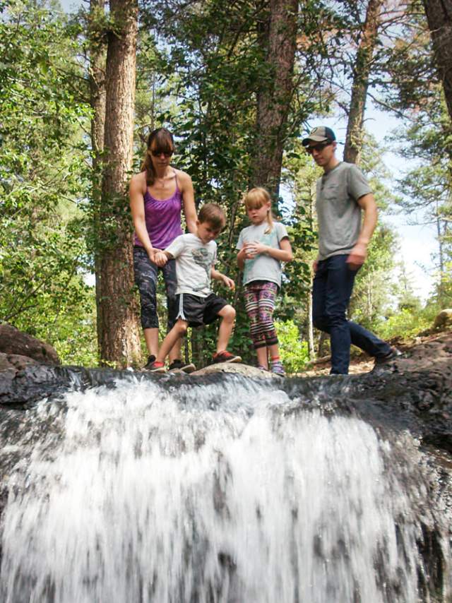 Family Of Four On Top Of A Waterfall In The Woods