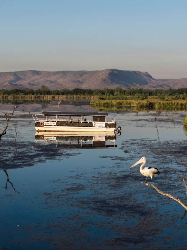 A boat floating on Lake Kununurra, with Elephant Rock/Sleeping Buddha visible in the background