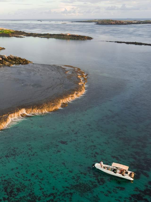 Aerial view of tour boat at Waterfall Reef with islands visible in the background