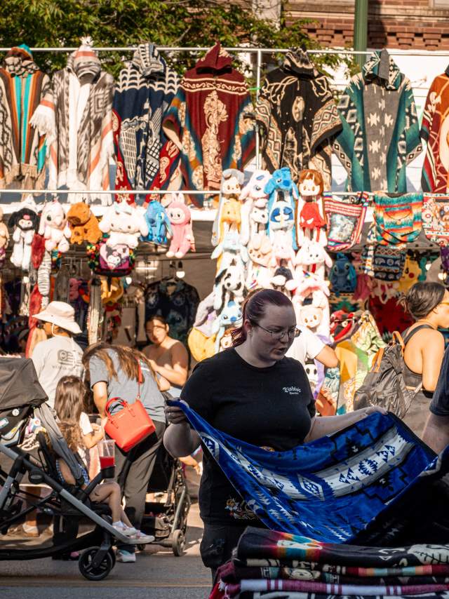 People shopping in the South Omaha neighborhood looking at tapestries.