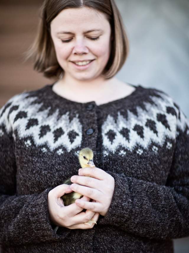 Kvinne som holder en liten kylling i hendene