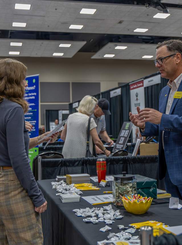 two women at Salina Business Expo 2025 talking to a business man at a booth