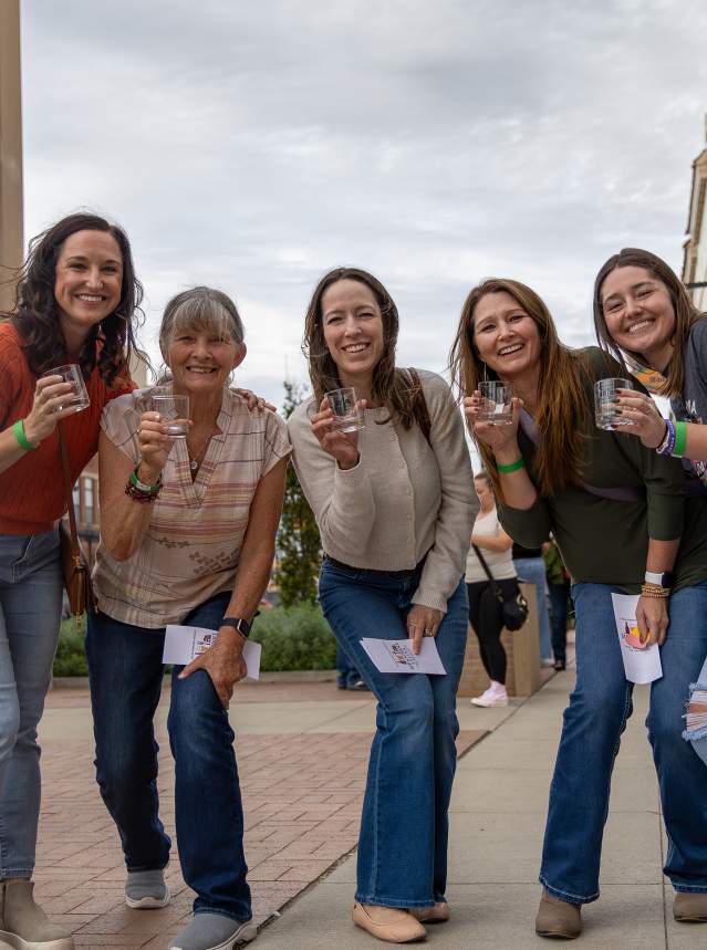 a group of 5 women posing for a picture with drinks in their hands at Sip and Stroll in Salina, Kansas