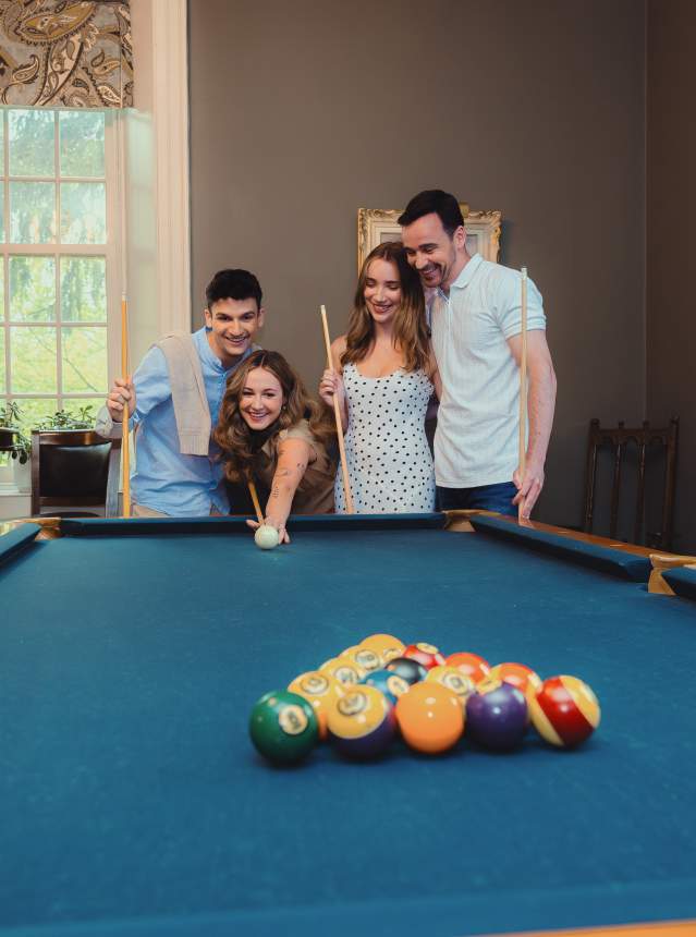 Friends playing pool at a bed and breakfast.