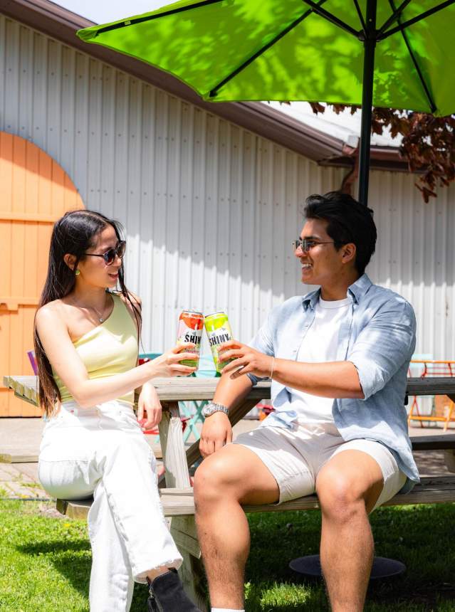 Couple drinking ciders on a picnic bench