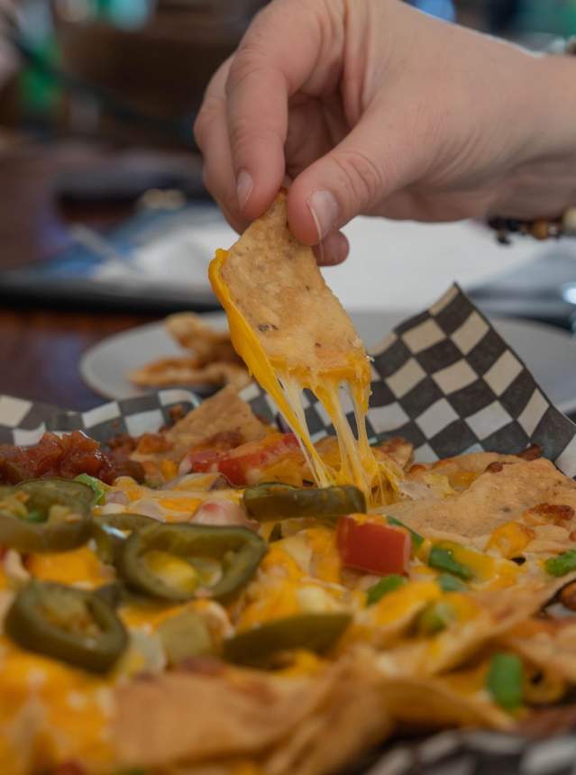 Hand grabbing from a plate of nachos