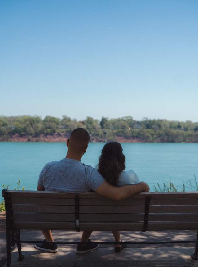 Couple sitting on a bench, staring at the waterfront