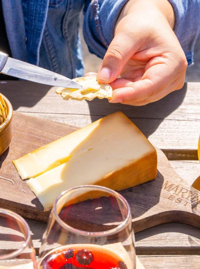 Hand spreading cheese on a cracker.