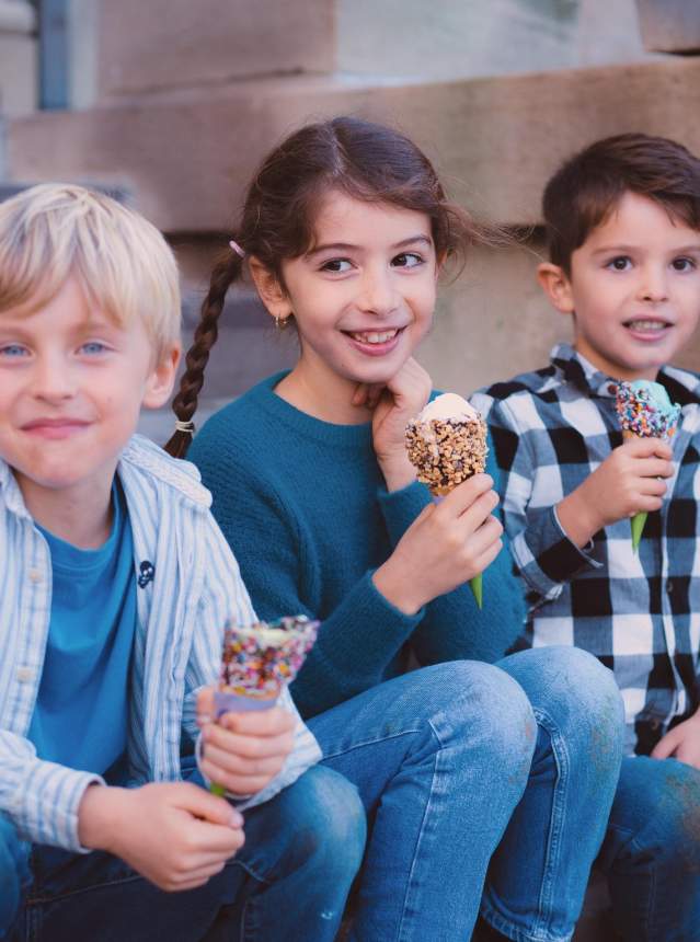Three children sitting on a staircase eating ice cream