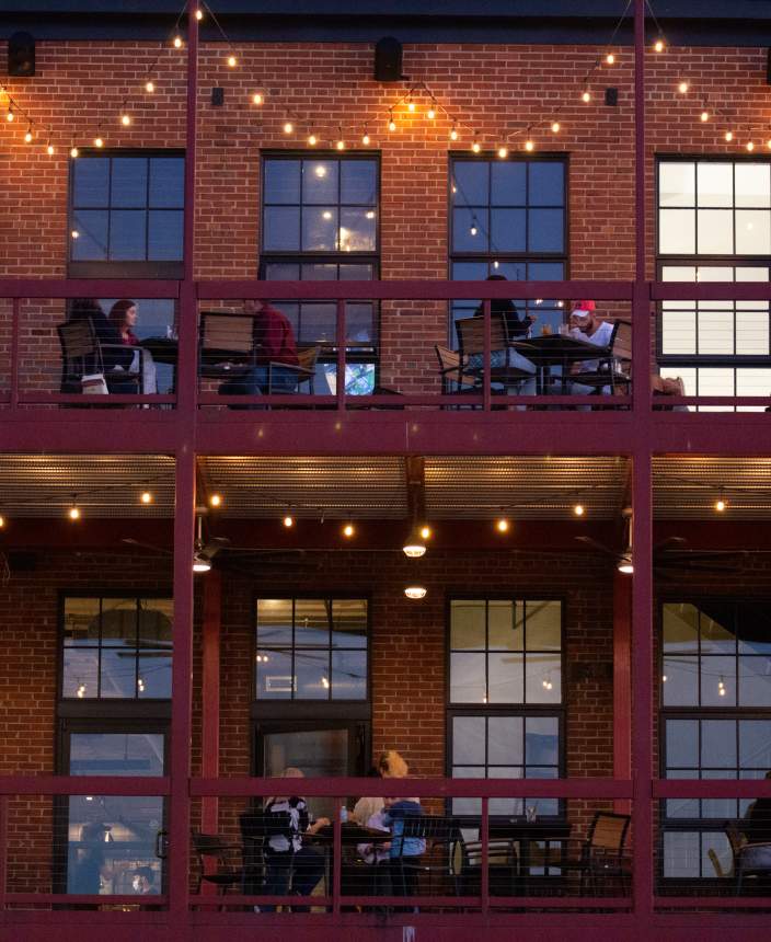 people eating outside on a two-story balcony