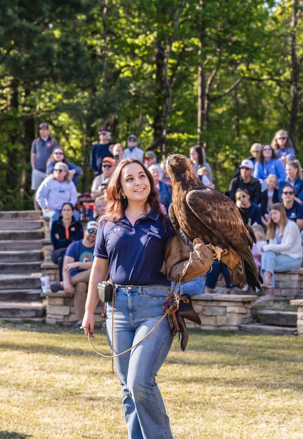 raptor center employeee standing in front of crowd with eagle